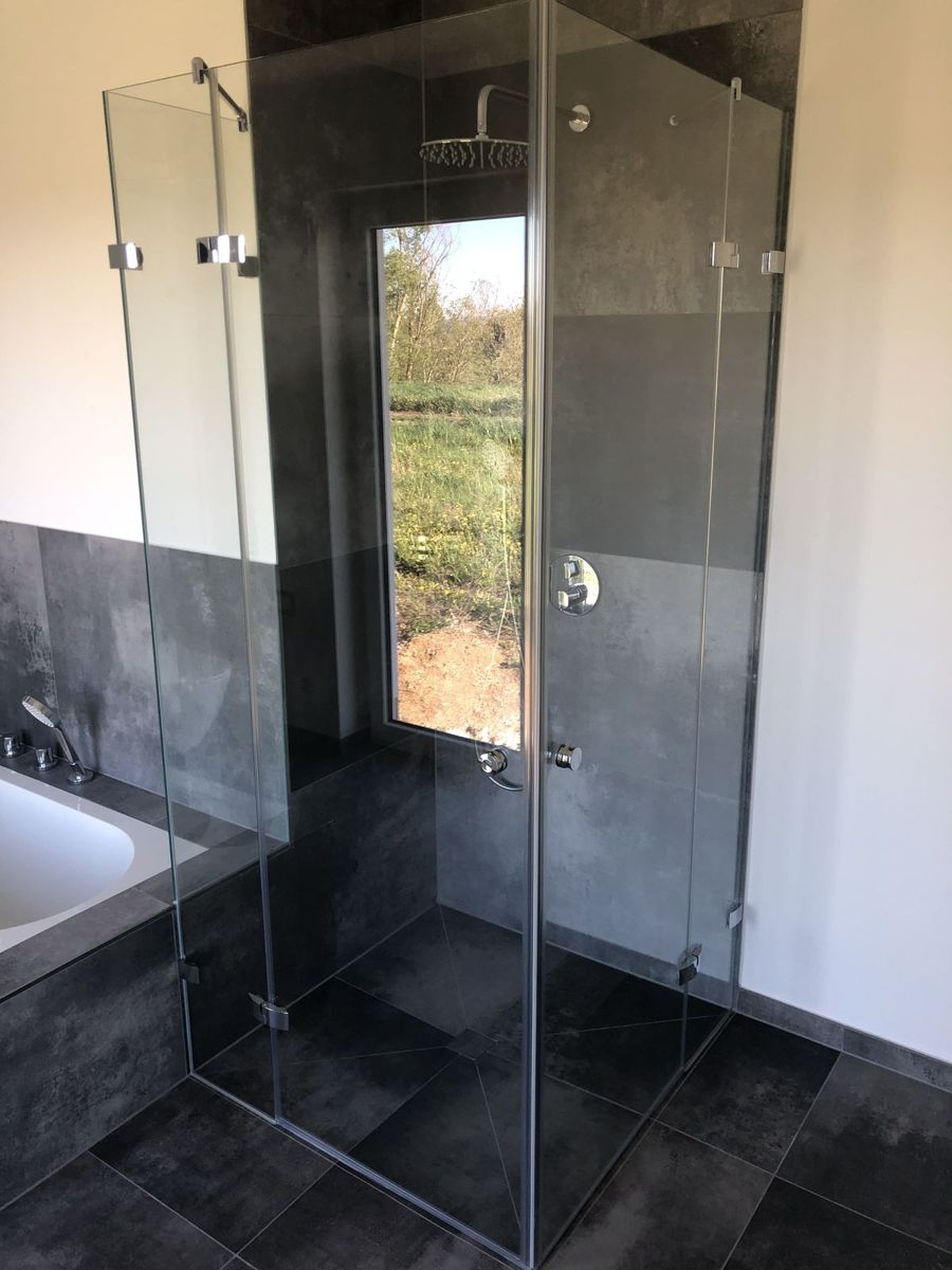 Rahmenlose, bodengleiche Eckdusche aus Glas neben Badewanne, SK Glas